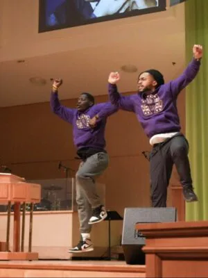 A team from the Psi lota Chapter of Omega Psi Phi, a historically Black fraternity, performs a hop, a dance style characterized by rhythmic jumping.