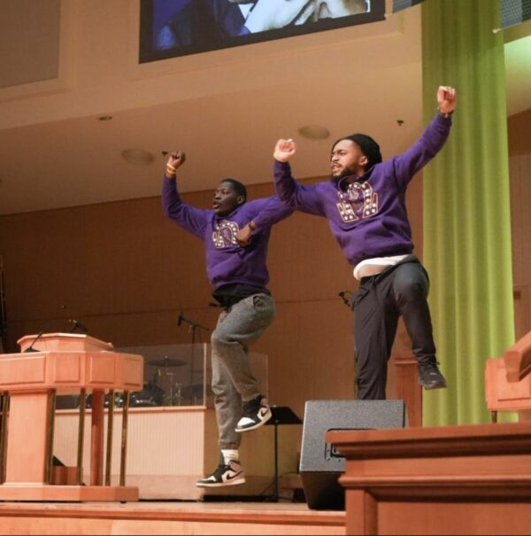 A team from the Psi lota Chapter of Omega Psi Phi, a historically Black fraternity, performs a hop, a dance style characterized by rhythmic jumping.